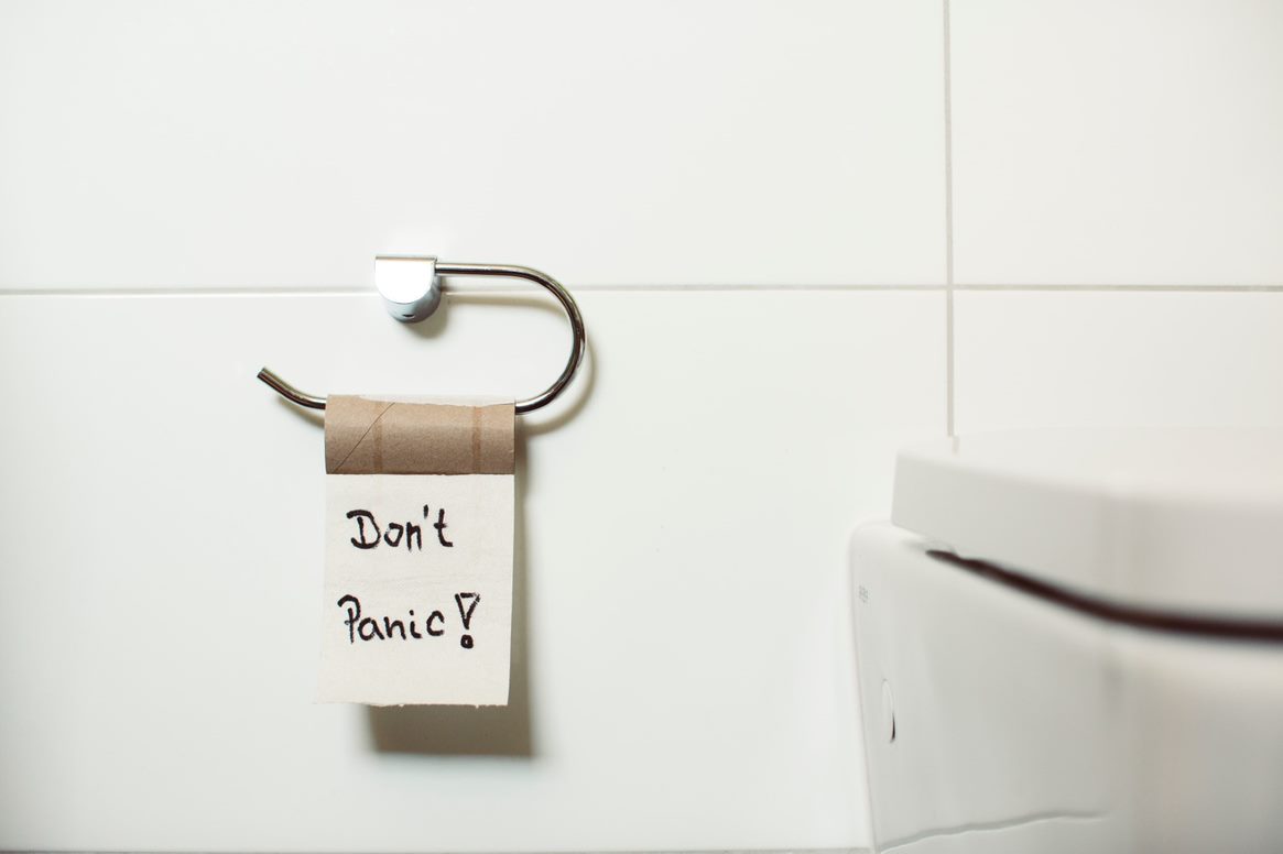 Empty toilet paper roll with one piece hanging off of roll, with "Don't Panic?" written in black. Toilet bowl visible in bottom right corner of image
