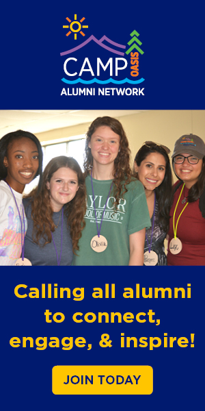 A group of five smiling young adults stand together in a well-lit room, wearing name tags. Text above invites alumni to connect. Tone is warm and inviting.