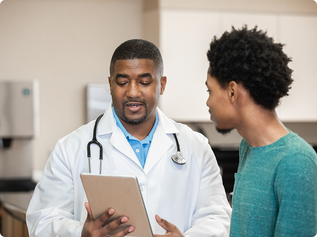 A male doctor discusses treatments with a young adult male patient