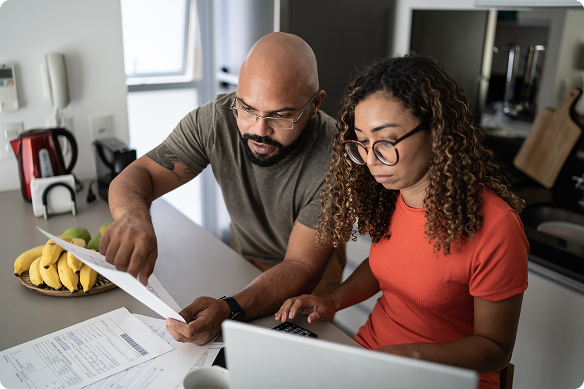 Couple discusses insurance paperwork using their computer.