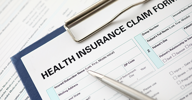 A pen, clipboard, and health insurance claim form
