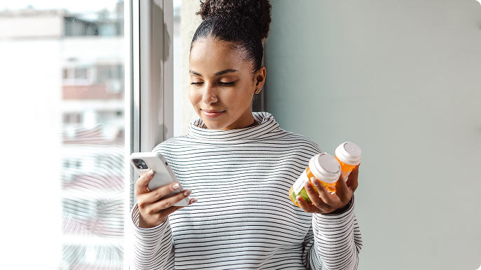 A patient looks at and holds a bottle of pills while talking on the phone.
