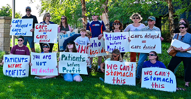 An image of people protesting, including signs that read “We can’t stomach this” and “patients before profit.”