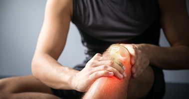 A seated figure holding their glowing red knee with a kneecap superimpose