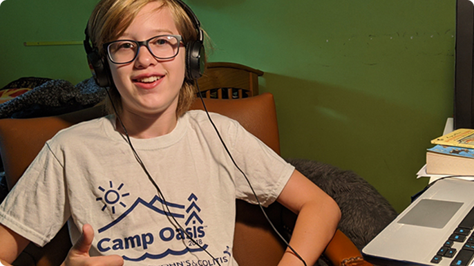 A young teen at home, wearing a Camp shirt, giving the thumbs up.