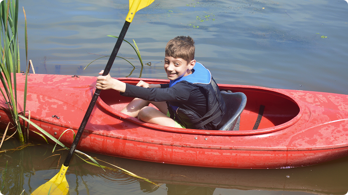 A smiling young boy in a canoe.