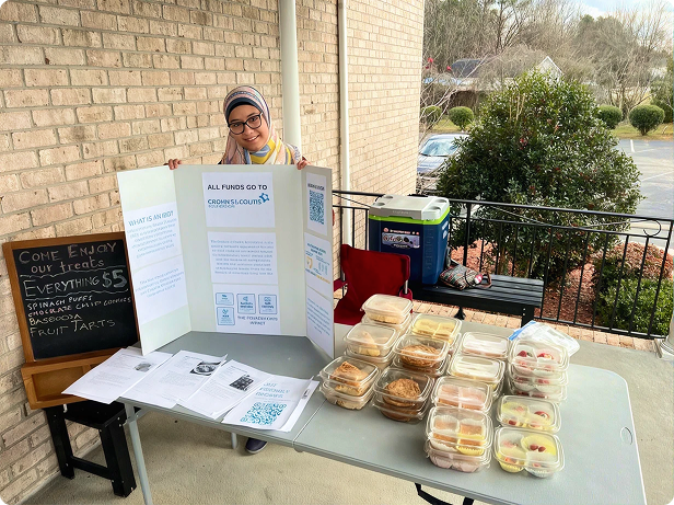 A woman displays Foundation information alongside baked treats at her bake sale fundraiser.