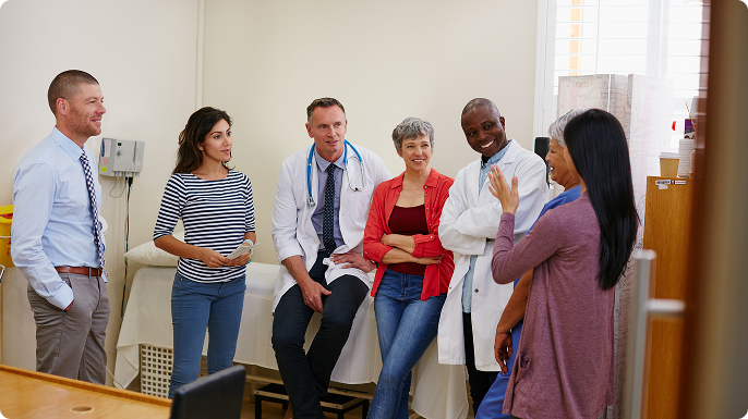 A group of patients and doctors having a conversation in an examining room.