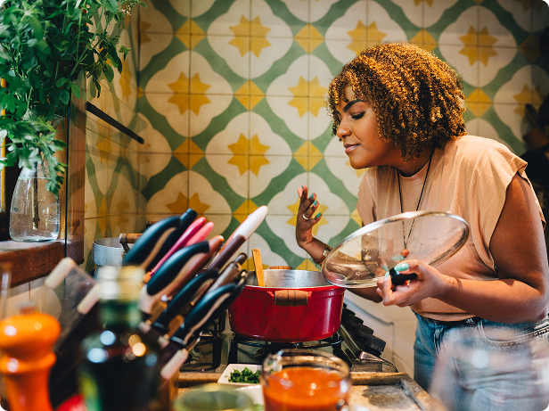 A woman smells the delicious aroma of the recipe she’s making on her stove.