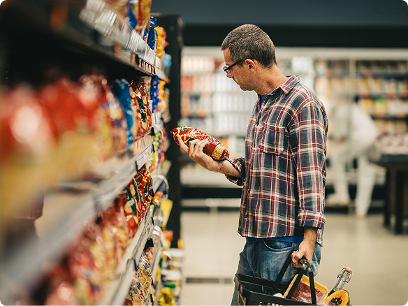 An adult man browses food in the supermarket.