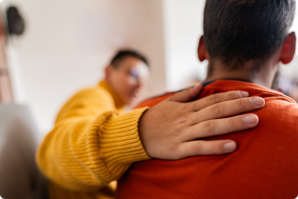 A man pats another man on the shoulder to comfort him.