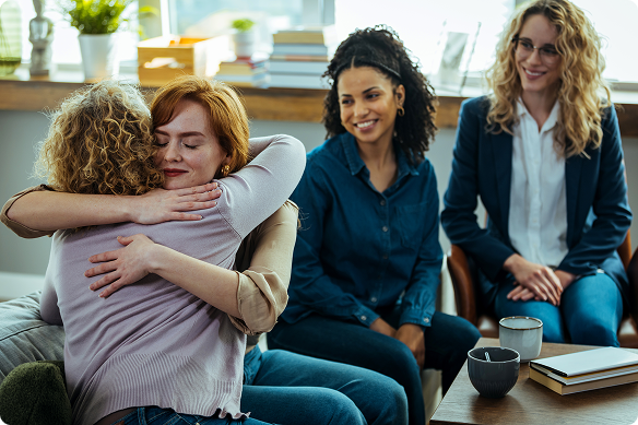 Two women hug as rest of support group looks on.
