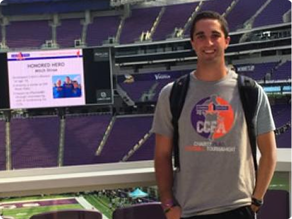 Mitchell, wearing a “Touch of Football” t-shirt and standing in a football stadium.