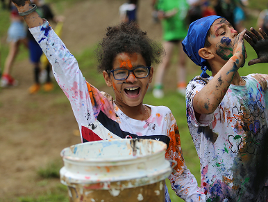 A young girl and boy, covered in paint and having a lot of fun playing and making a mess