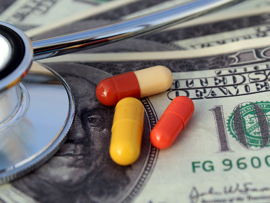 Medications and a stethoscope rest on hundred-dollar bills
