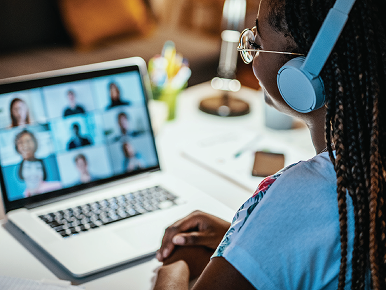Woman with headphones sitting in on a telehealth session