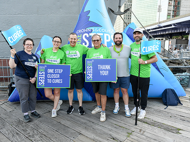 A team in posing with team shirts and “thank you” signs at their Take Steps Walk.
