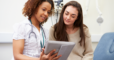 A young woman reviews information on a tablet with her doctor