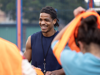 Young, smiling athletic coach looking confident as his team gets ready.