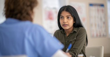 Pensive young woman discusses her symptoms with a doctor.