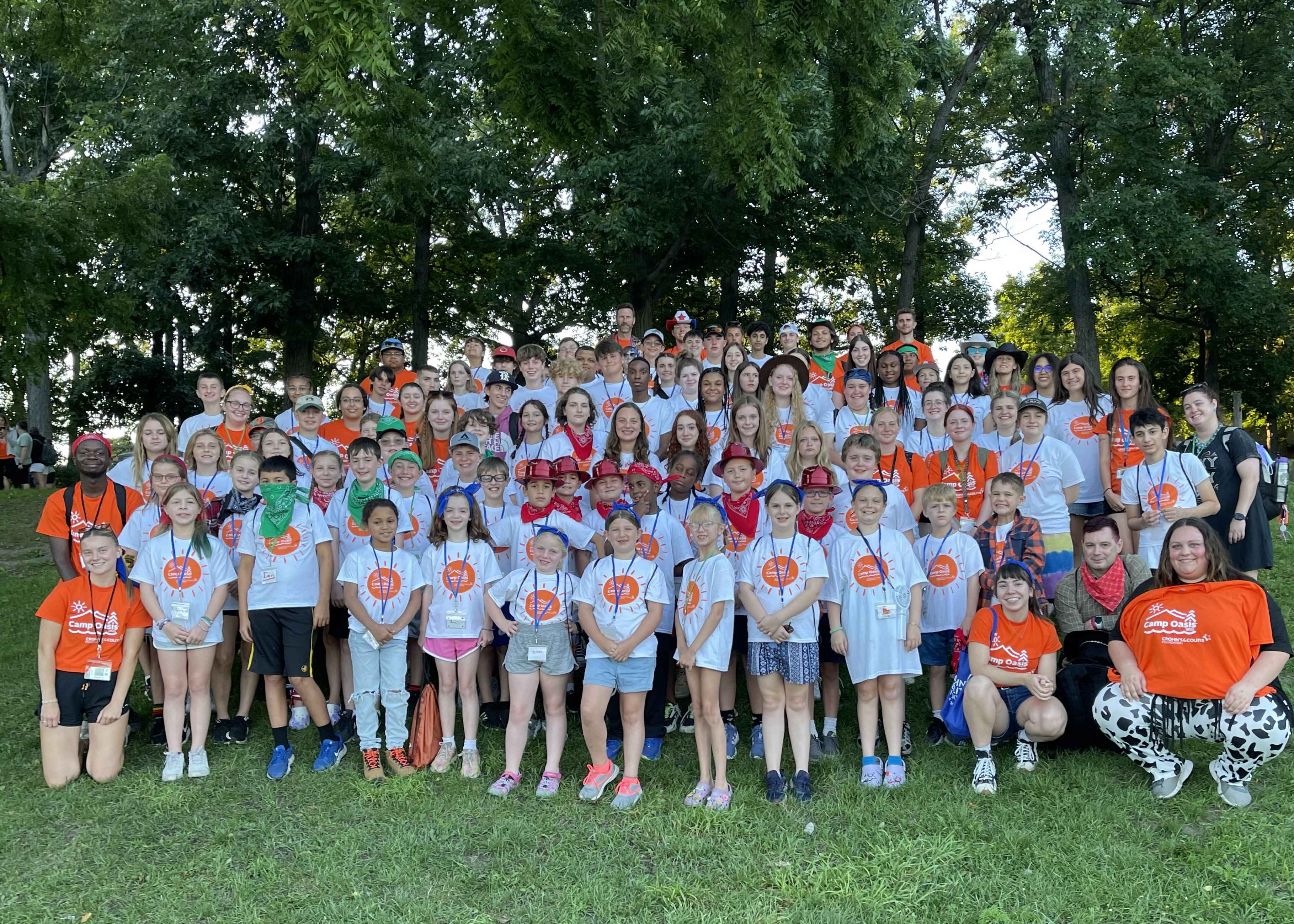 Group of campers gathered together on a grassy hill in matching t-shirts