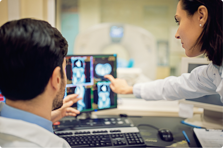Two physicians reviewing a patient abdomen scan on a computer.