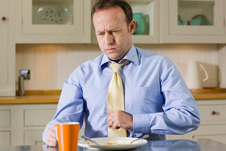 Man eating breakfast, experiencing stomach distress
