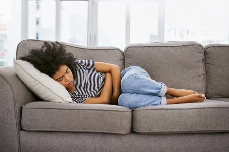 Woman lying on couch with stomach ache