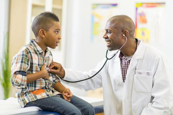 Doctor checking boy's heartbeat with stethoscope; doctor's office scene