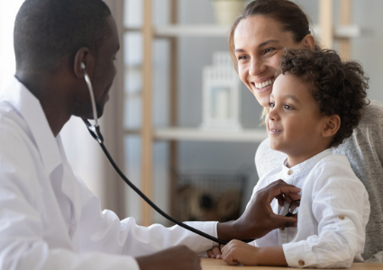 Pediatrician checking smiling child patient with stethoscope