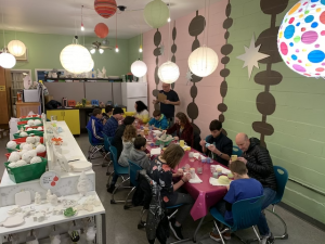 youth and families eating at a table in a room decorated with paper lanterns